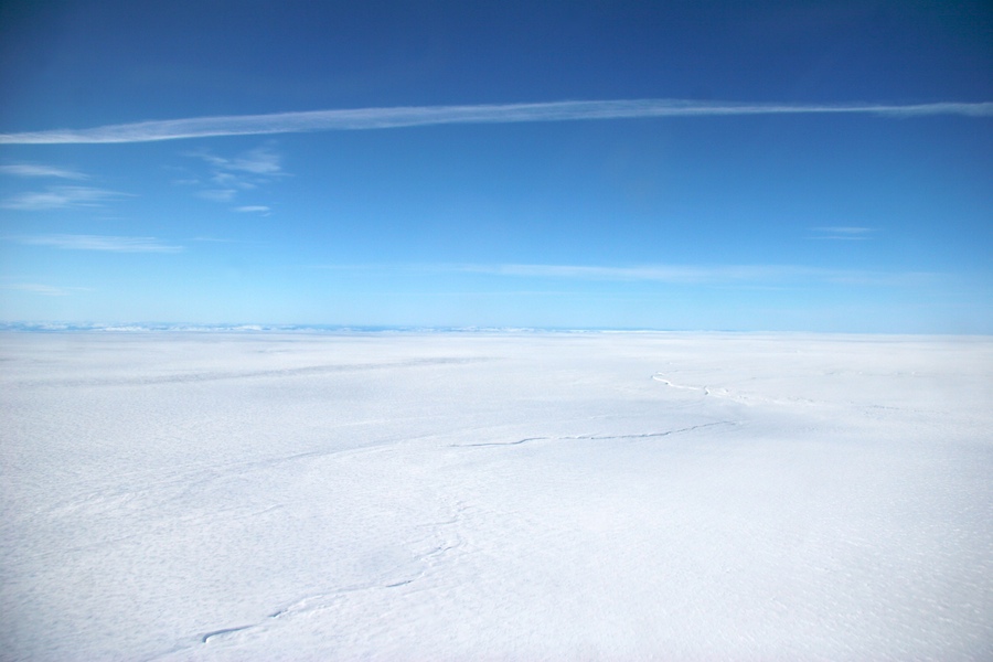 A crack in the otherwise featureless  Greenland ice sheet near Jakobshavn stretches towards the horizon.
